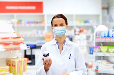 female apothecary in mask with drug at pharmacy
